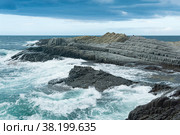 Rocky seashore formed by columnar basalt against the backdrop of a stormy sea, coastal landscape of the Kuril Islands. Стоковое фото, фотограф Евгений Харитонов / Фотобанк Лори