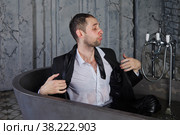 Emotional young businessman man in suit lies in water in bath and spits out aqua. Person's gesture indicates relaxation, creative imagination, or indifference. Concept of human emotions. Copy space. Стоковое фото, фотограф Aleksandr Golubev / Фотобанк Лори