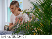 Young woman feels pain in her heart. Unhealthy female, sit on couch and holding her chest, feeling uncomfortable. Concept of health problems, heart attacks and ailments. Selective focus in foreground. Стоковое фото, фотограф Aleksandr Golubev / Фотобанк Лори