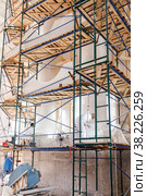 Workers restore white walls on scaffolding in large room. Construction works, interior repairs, restoration and reconstruction of antique buildings are underway. Стоковое фото, фотограф Aleksandr Golubev / Фотобанк Лори