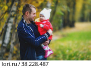 Child in arms of man's father. Autumn day. Pretty, happy, blue-eyed one-year-old girl in red coat and white hat. Charming baby shows emotions close-up. Concept of healthy child and parenting. Стоковое фото, фотограф Aleksandr Golubev / Фотобанк Лори