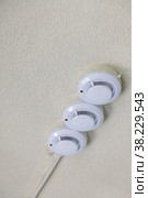 Fire detectors on ceiling. Smoke and fire detector in grey on grey wall. Triple smoke detector on textured ceiling. Vertical background with space for your lettering or logo. Стоковое фото, фотограф Aleksandr Golubev / Фотобанк Лори