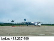 Standing plane and helicopter taking off in the background at the airport of Kunashir island (2022 год). Редакционное фото, фотограф Евгений Харитонов / Фотобанк Лори