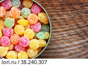 Colorful multicolored sucking sweets Montpensier lollipops in a round tin box on a wooden background close-up with copy space, top view. Стоковое фото, фотограф Андрей С / Фотобанк Лори