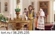 Sanctuary lamp with lit candles in the Orthodox Church - a baby's baptism is taking place in the background. Стоковое видео, видеограф Константин Шишкин / Фотобанк Лори