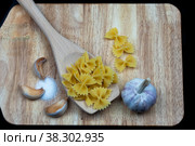 Pasta in the form of butterflies on a wooden board with garlic and salt close-up. Стоковое фото, фотограф Ярославский Максим / Фотобанк Лори