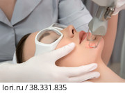 Therapist beautician makes a laser rejuvenation for the model by apparatus in a beauty salon. Стоковое фото, фотограф Юлия Тарасова / Фотобанк Лори