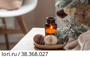 The concept of New Year and Christmas. Home warmth in cold weather. Still-life. Scandinavian-style paper Christmas tree toys on fir branches and candles on a coffee table in the living room interior. Стоковое фото, фотограф Photojuli / Фотобанк Лори