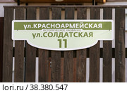 Адресная табличка на заборе с современным (Красноармейская) и историческим (Солдатская) названием улицы. Город Руза, Московская область, Россия (2022 год). Редакционное фото, фотограф Наталья Николаева / Фотобанк Лори
