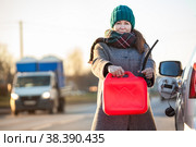 Женщина водитель показывает пустую красную канистру для топлива, стоит возле заглохшего автомобиля. Стоковое фото, фотограф Кекяляйнен Андрей / Фотобанк Лори