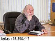 Мужчина задумчиво смотрит вверх, пенсионер на рабочем месте в кресле. Стоковое фото, фотограф Кекяляйнен Андрей / Фотобанк Лори