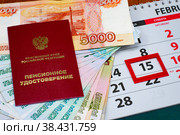 День выплаты пенсии. Календарь и пенсионное удостоверение с денежными купюрами лежат на столе. Стоковое фото, фотограф Анна Аникова / Фотобанк Лори