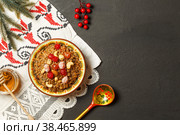 Kutya, a porridge made from Emmer wheat with fruit and nuts. Top view, on a white napkin with embroidery and fir branches. Black background with space. Стоковое фото, фотограф Bogdanova Mariia / Фотобанк Лори