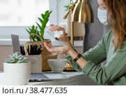Коронавирус и грипп. Деловая женщина, работающая в офисе в защитной маске. Деловая женщина на карантине из-за коронавируса в защитной маске. Работа из дома. Моет руки дезинфицирующим гелем. Стоковое фото, фотограф Photojuli / Фотобанк Лори