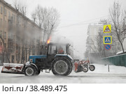 Москва. Город  засыпало снегом. Колесный трактор убирает улицу (2021 год). Редакционное фото, фотограф Наталья Николаева / Фотобанк Лори