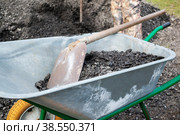 wheelbarrow with a shovel and gravel. as part of a construction project, a man is transporting rubble on a hand wheelbarrow. Paving the road with gravel. Construction with your own hands. Стоковое фото, фотограф Оксана Медведева / Фотобанк Лори