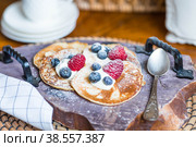 Delicious pancakes with honey, blueberries and raspberries. Next to it is a wooden barrel with an inscription in Russian: "honey". The concept of the Maslenitsa holiday. Стоковое фото, фотограф Photojuli / Фотобанк Лори