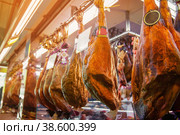 Spanish ham, whole large pieces hanging on hooks on the market. (2013 год). Стоковое фото, фотограф Оксана Медведева / Фотобанк Лори
