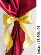 Golden bow on red cloth on a white background. Стоковое фото, фотограф Aleksandra Selivanova / Фотобанк Лори