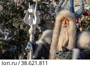 Якутский Дед Мороз Чысхаан на фоне заснеженной новогодней елки (2023 год). Редакционное фото, фотограф Николай Винокуров / Фотобанк Лори