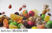 Multicolored dried fruits and nuts in colored glaze fall on white surface in slow motion. Стоковое видео, видеограф Mixail59 / Фотобанк Лори