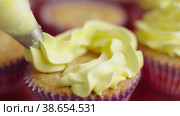 Decorating cupcake with cream using cooking bag. Squeezing cream on delicious cupcakes for party. Close-up. Home baking concept. Стоковое видео, видеограф Mixail59 / Фотобанк Лори
