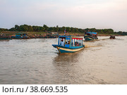 Tourists on motor boats go to see the floating village on Tonle Sap lake. Siem reap, Cambodia (2013 год). Редакционное фото, фотограф Юлия Бабкина / Фотобанк Лори