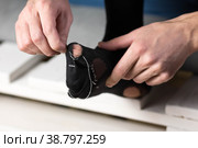 A man sews a black torn sock with white threads. Closeup. Isolated on a white background. Стоковое фото, фотограф Плотников Дмитрий / Фотобанк Лори