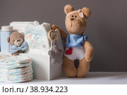 Wooden toys, a bear in a bow tie, a stack of diapers and baby supplies on the changing table. Space for text. Стоковое фото, фотограф Photojuli / Фотобанк Лори