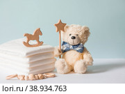 Wooden toys, a bear in a bow tie, a stack of disposable diapers and baby supplies on the changing table. Space for text. Стоковое фото, фотограф Photojuli / Фотобанк Лори