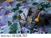 medicines and pills are lying in a small shopping cart against the background of money euro dollars 100 500. pills are poured out of the cart for money the problem of the cost of medicines expensive m. Стоковое фото, фотограф Meshkov Sergey / Фотобанк Лори