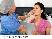 Cosmetologist consulting woman before procedures for lip augmentation. Стоковое фото, фотограф Яков Филимонов / Фотобанк Лори