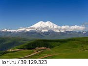 Great nature mountain landscapes. Fantastic perspective of caucasian snow inactive volcano Elbrus with green fields and road to it and clearly blue sky background. Russia. Стоковое фото, фотограф Евгений / Фотобанк Лори