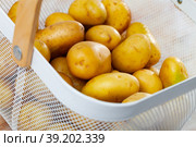 Fresh potatoes in steel mesh bucket on wooden table. Стоковое фото, фотограф Яков Филимонов / Фотобанк Лори