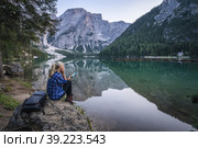 Woman reading e-book at Pragser Wildsee with reflected mountains on lake surface. Dolomites, Italy. Стоковое фото, фотограф Igor Tichonow / Фотобанк Лори