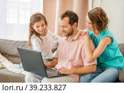 Happy family, mom, dad and daughter are sitting on couch and looking at laptop monitor together. Стоковое фото, фотограф Мария Мороз / Фотобанк Лори