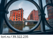 Speicherstadt warehouse district in Hamburg, Germany, Europe. Old brick buildings and channel of Hafencity quarter. UNESCO heritage. Shoot thought cast-iron creative concept (2019 год). Стоковое фото, фотограф Igor Tichonow / Фотобанк Лори