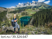 Woman with backpack enjoy Carezza lake from top hill - Lago di Carezza, Karersee, Bolzano province, South tyrol, Italy. Стоковое фото, фотограф Igor Tichonow / Фотобанк Лори