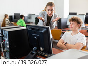 Frustrated teacher talking to neglectful teenage student in computer class. Стоковое фото, фотограф Яков Филимонов / Фотобанк Лори