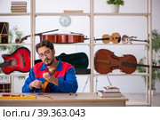 Young man repairing musical instruments at workshop. Стоковое фото, фотограф Elnur / Фотобанк Лори
