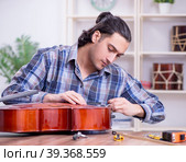 Young handsome repairman repairing cello. Стоковое фото, фотограф Elnur / Фотобанк Лори