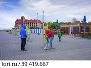 A man with children in multi-colored jackets standing at the public gyms waterfront city (2016 год). Редакционное фото, фотограф Виктория Кольцова / Фотобанк Лори