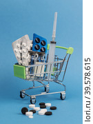 Shopping trolley with pills and medicines, medical ampoules and a syringe. Blue background. Concept: purchase of medicines, medicines, rise in price of medicines. Стоковое фото, фотограф Регина Ерофеева / Фотобанк Лори
