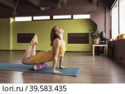 A woman in sportswear performs a myofascial massage of the leg muscles with a roller, trains on a mat in a room with a deflection back. Стоковое фото, фотограф Сергей Чайко / Фотобанк Лори