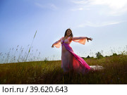 Beautiful girl in a lush pink ball gown in green field during blooming of flowers and blue sky on background. Model posing on nature landscape as princess from fary tale. Partial focus. Стоковое фото, фотограф Кривошеина Елена Леонидовна / Фотобанк Лори