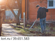 Gardener raking fall leaves in garden. Copy space. Стоковое фото, фотограф Кутина Татьяна / Фотобанк Лори