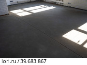 The leveled rough floor in a house under construction with a semi-dry cement screed is a smooth surface with light from the windows. Стоковое фото, фотограф Ольга Симонова / Фотобанк Лори