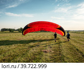 Пилот готовит мотопараплан ко взлёту. The pilot prepares a motorcycle paraglider for takeoff. (2022 год). Редакционное фото, фотограф Евгений Романов / Фотобанк Лори