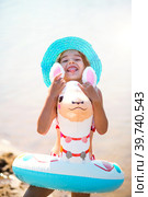 Girl in a hat it stands on the shore with inflatable circle in the shape of a lama. Inflatable alpaca for a child. Sea with a sandy bottom. Beach holidays, swimming, tanning, sunscreens. Стоковое фото, фотограф Ольга Симонова / Фотобанк Лори
