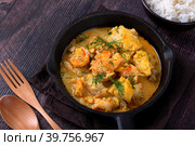 Fish curry with codfish, pollack and shrimps with coconut milk served in cast iron pan. Стоковое фото, фотограф Оксана Чаюн / Фотобанк Лори